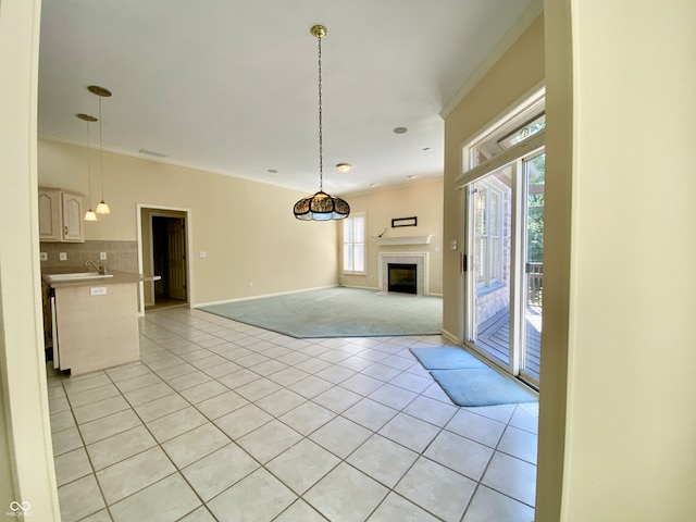 unfurnished living room featuring ornamental molding, sink, light carpet, and a fireplace