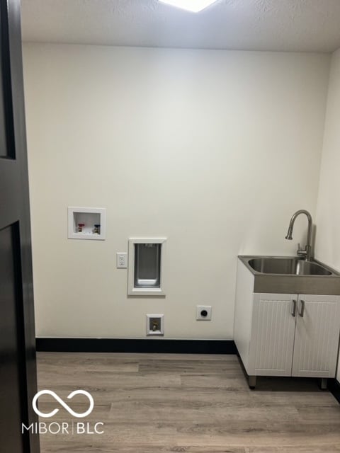 laundry area featuring hookup for an electric dryer, light hardwood / wood-style flooring, cabinets, and sink