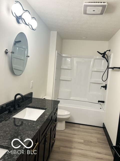 full bathroom featuring a textured ceiling, toilet, vanity, hardwood / wood-style flooring, and shower / bathtub combination