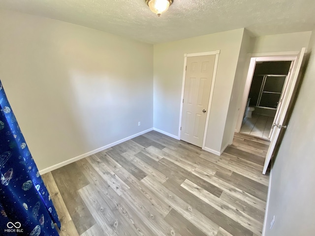 unfurnished bedroom with a closet, a textured ceiling, and hardwood / wood-style flooring