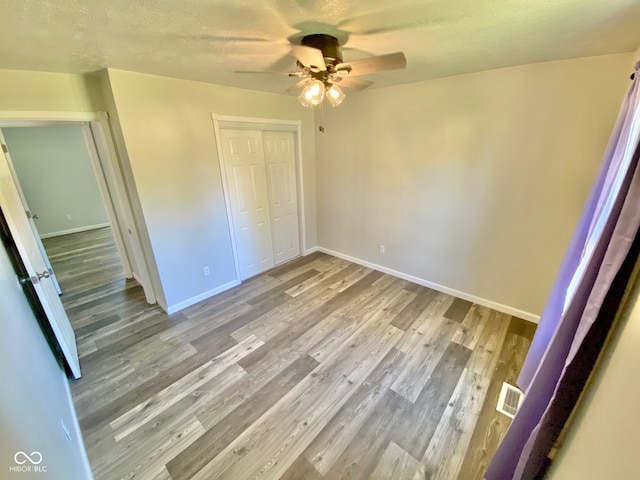 unfurnished bedroom with ceiling fan, wood-type flooring, and a closet