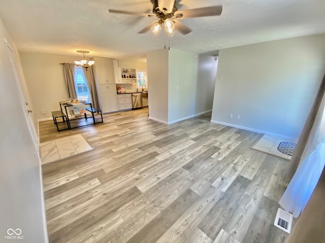 unfurnished living room with a textured ceiling, ceiling fan with notable chandelier, and light wood-type flooring