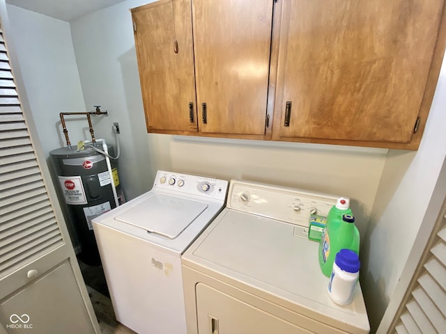 clothes washing area featuring cabinets, electric water heater, and washing machine and clothes dryer