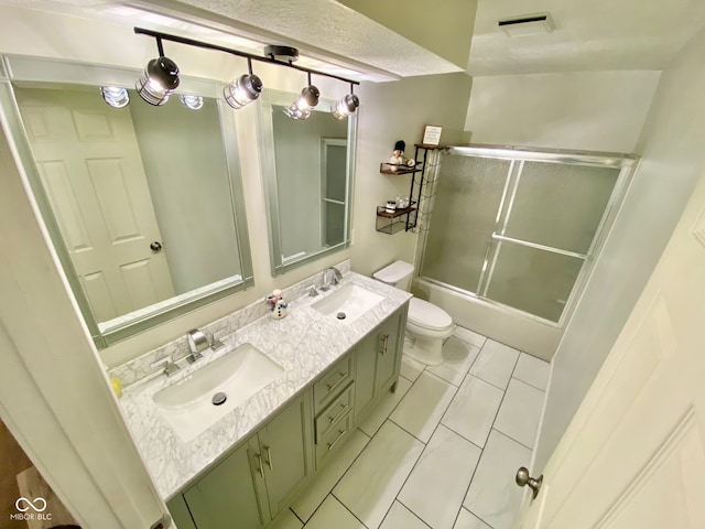 full bathroom featuring shower / bath combination with glass door, vanity, tile patterned flooring, and toilet