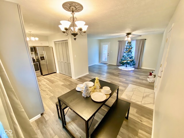 dining room featuring a textured ceiling, ceiling fan with notable chandelier, and light wood-type flooring