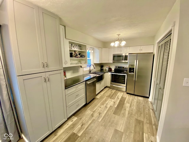 kitchen with a notable chandelier, white cabinets, light hardwood / wood-style flooring, appliances with stainless steel finishes, and decorative light fixtures