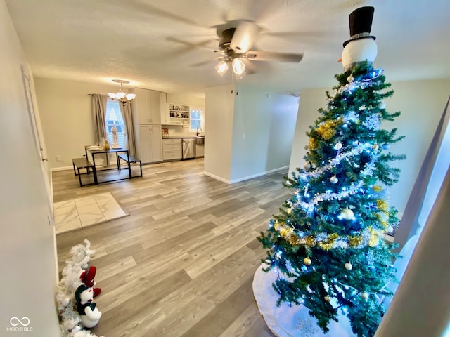 interior space with a textured ceiling, ceiling fan with notable chandelier, and light hardwood / wood-style floors