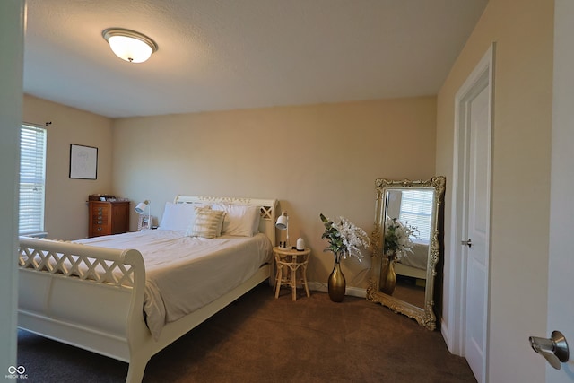 bedroom featuring dark carpet and multiple windows