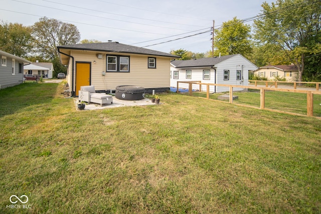 rear view of house featuring a lawn and a hot tub