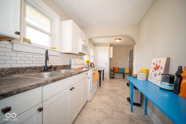 kitchen featuring tasteful backsplash, white appliances, sink, white cabinets, and a textured ceiling