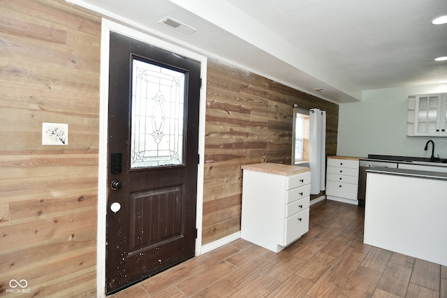 interior space featuring wooden walls, white cabinetry, hardwood / wood-style flooring, and a healthy amount of sunlight