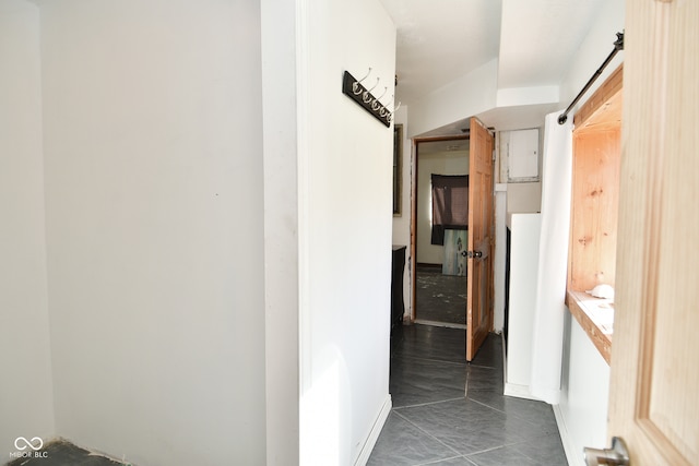 hall with dark tile patterned floors and a barn door