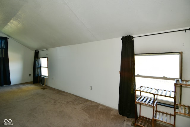 carpeted spare room featuring vaulted ceiling