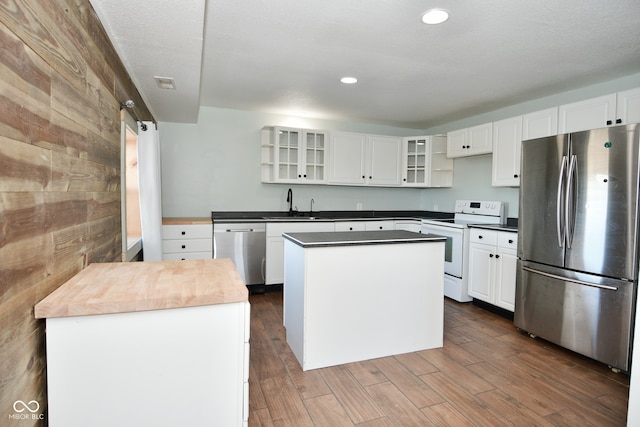 kitchen with white cabinetry, appliances with stainless steel finishes, dark hardwood / wood-style flooring, and a kitchen island