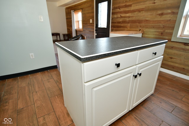 kitchen featuring wooden walls, white cabinets, dark hardwood / wood-style floors, and a center island