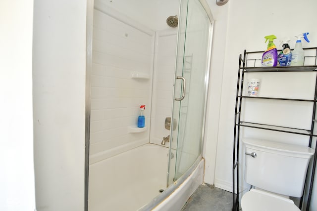 bathroom with concrete floors, bath / shower combo with glass door, and toilet