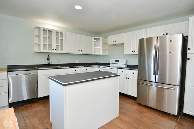 kitchen with appliances with stainless steel finishes, white cabinets, dark wood-type flooring, and a kitchen island