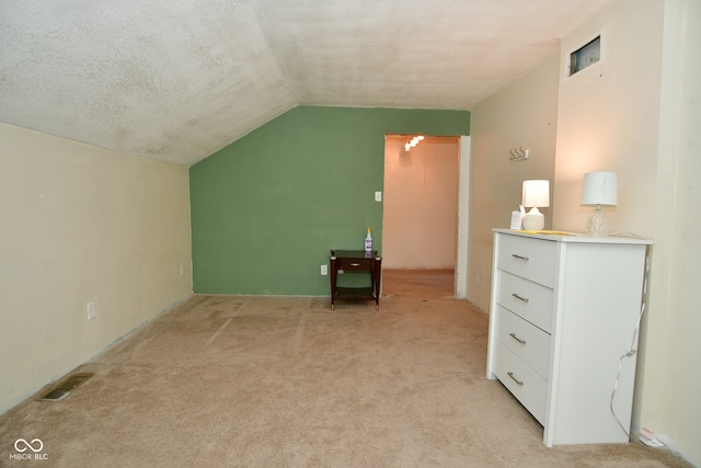 additional living space featuring lofted ceiling, a textured ceiling, and light colored carpet