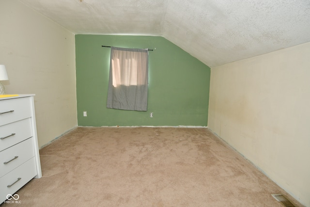 bonus room featuring a textured ceiling, vaulted ceiling, and light colored carpet