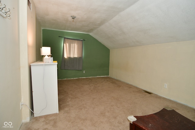 additional living space featuring lofted ceiling, a textured ceiling, and light colored carpet