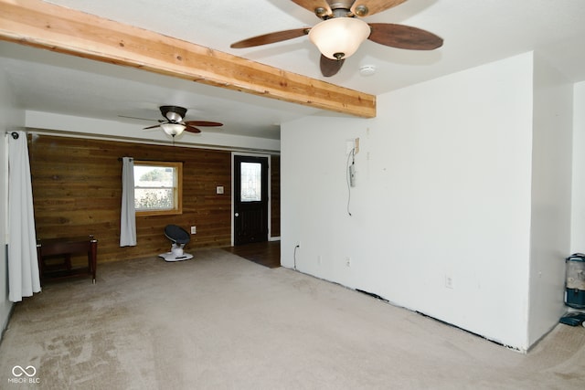 interior space featuring light carpet, wood walls, beam ceiling, and ceiling fan