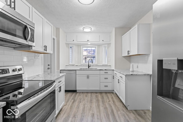 kitchen featuring light hardwood / wood-style flooring, stainless steel appliances, sink, light stone countertops, and white cabinets