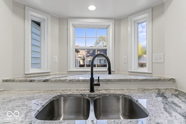 interior details featuring light stone countertops and sink