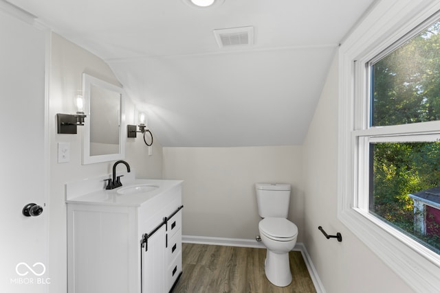 bathroom with vanity, toilet, hardwood / wood-style flooring, and lofted ceiling