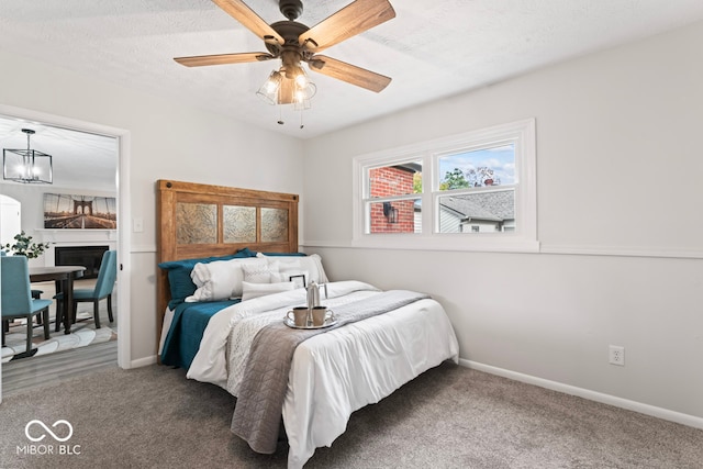 bedroom with a textured ceiling, carpet flooring, a fireplace, and ceiling fan