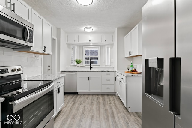 kitchen with appliances with stainless steel finishes, white cabinetry, and sink