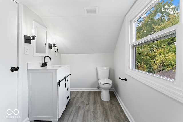 bathroom featuring vanity, toilet, hardwood / wood-style flooring, and lofted ceiling