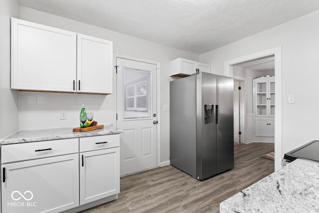 kitchen with white cabinetry, stainless steel refrigerator with ice dispenser, a textured ceiling, and wood-type flooring