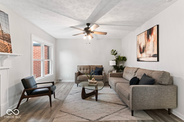 living room with a textured ceiling, hardwood / wood-style flooring, and ceiling fan