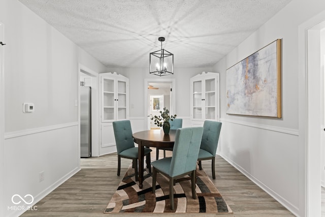 dining space with a textured ceiling, light hardwood / wood-style flooring, and a chandelier