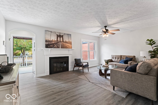 living room featuring ceiling fan, a textured ceiling, and dark hardwood / wood-style flooring