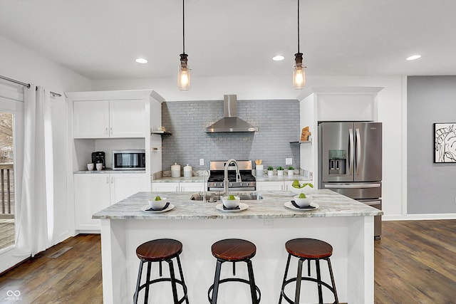 kitchen with white cabinets, wall chimney range hood, stainless steel appliances, sink, and light stone counters