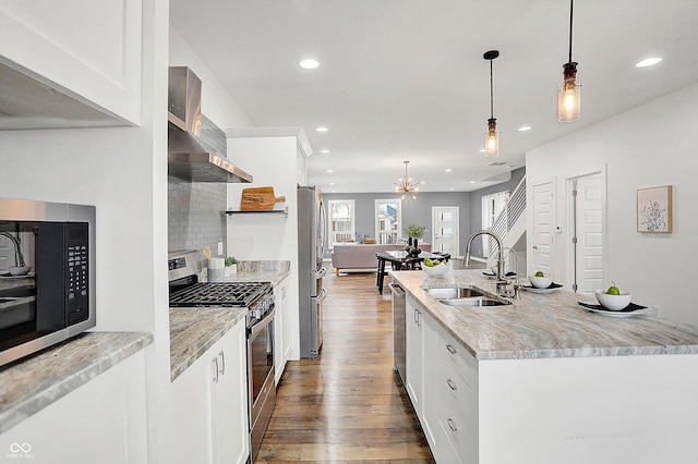 kitchen with appliances with stainless steel finishes, white cabinets, hanging light fixtures, and light stone countertops