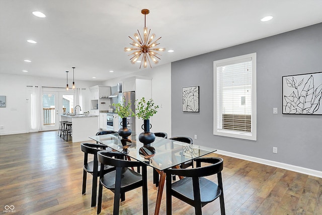 dining room with dark wood-type flooring, a wealth of natural light, and a notable chandelier