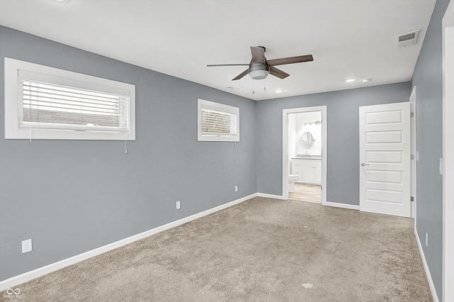 unfurnished bedroom featuring ceiling fan, connected bathroom, light colored carpet, and sink