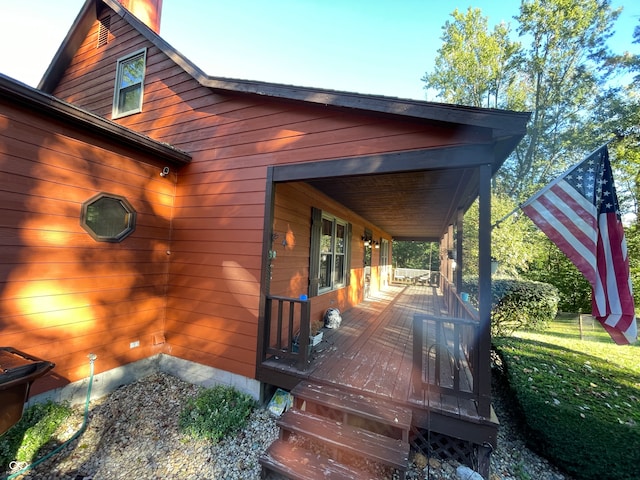 wooden deck with covered porch and a lawn