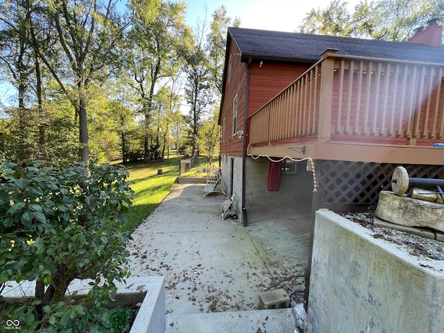 view of side of property featuring a wooden deck and a patio