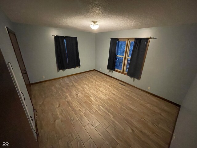 empty room with hardwood / wood-style floors and a textured ceiling