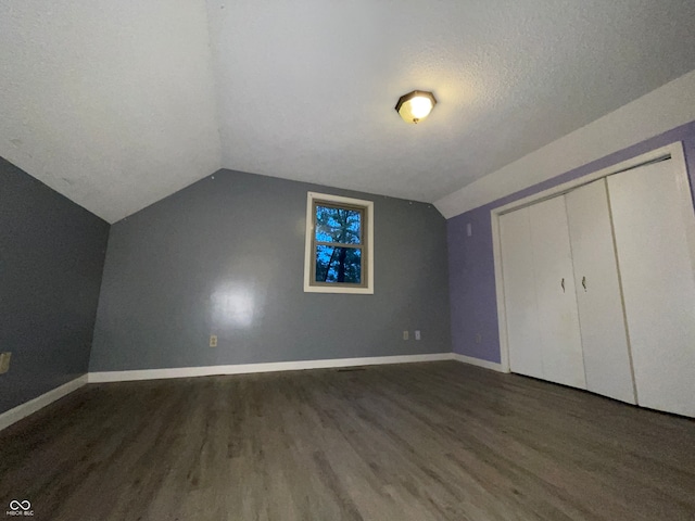 bonus room featuring a textured ceiling, vaulted ceiling, and dark hardwood / wood-style floors