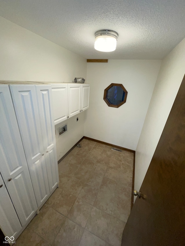 clothes washing area featuring electric dryer hookup, a textured ceiling, washer hookup, and cabinets