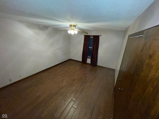 empty room with ceiling fan, a textured ceiling, and dark hardwood / wood-style flooring