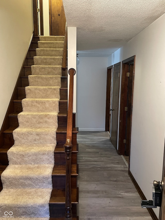 staircase featuring hardwood / wood-style flooring and a textured ceiling