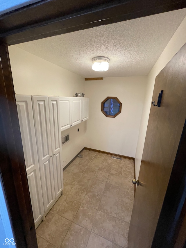 laundry room featuring cabinets, hookup for a washing machine, a textured ceiling, and light tile patterned flooring