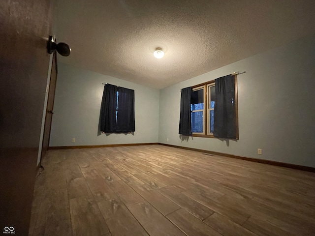 empty room with a textured ceiling and hardwood / wood-style floors