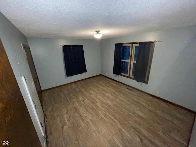 spare room featuring hardwood / wood-style flooring and a textured ceiling