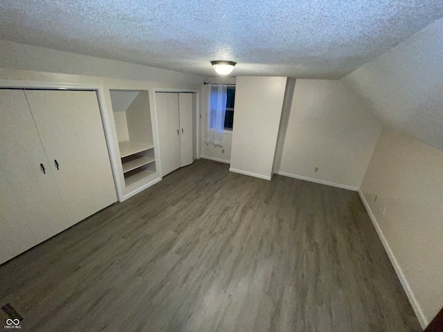 bonus room with lofted ceiling, hardwood / wood-style floors, and a textured ceiling